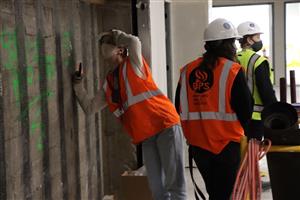 student looking at seismic work behing the walls